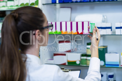 Pharmacist writing on clipboard while checking medicine