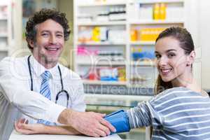 Pharmacist checking blood pressure of customer in pharmacy
