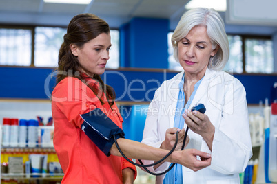 Pharmacist checking blood pressure of customer