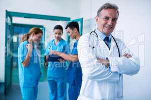 Portrait of smiling doctor standing with arms crossed in corrido