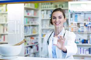 Smiling pharmacist showing medicine container in pharmacy