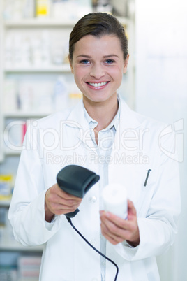 Smiling pharmacist using barcode scanner on medicine bottle in p