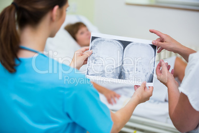 Nurses checking a x-ray of patient in hospital ward