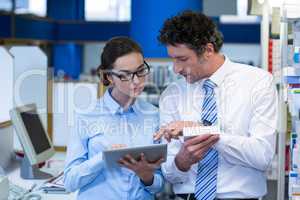 Pharmacists using digital tablet while checking medicine