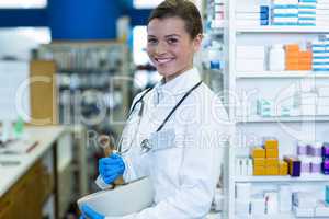 Pharmacist grinding medicine in mortal and pestle at pharmacy