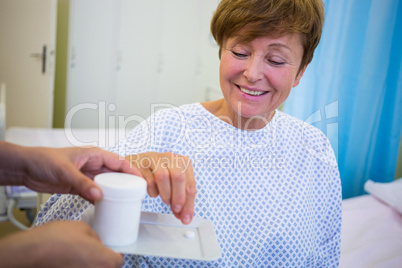 Nurse giving medication to senior patient