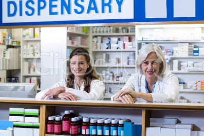 Smiling pharmacists standing at counter in pharmacy