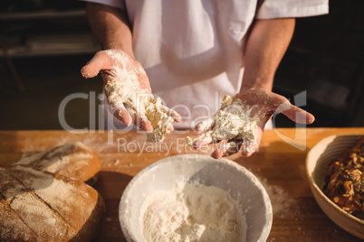 Mid-section of baker mixing flour by hand