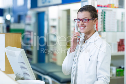 Smiling pharmacist talking on phone in pharmacy