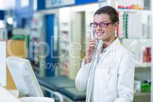 Smiling pharmacist talking on phone in pharmacy