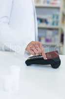 Pharmacist swiping card through payment terminal