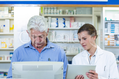 Pharmacists using digital tablet and computer
