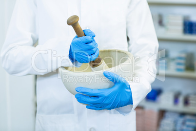 Pharmacist grinding medicine in mortal and pestle