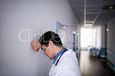 Sad doctor leaning against the wall