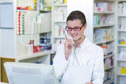 Pharmacist holding prescription paper while talking on phone