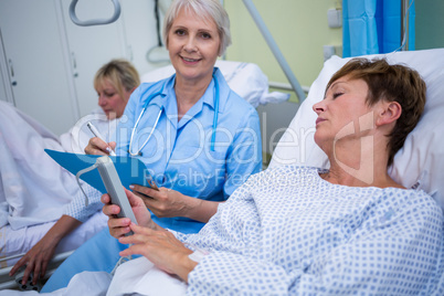 Patient using medical device and nurse sitting next to the bed