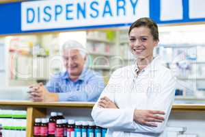 Pharmacist standing with arms crossed in pharmacy