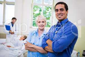 Smiling doctor and nurse standing with arms crossed