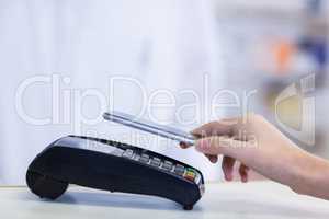 Woman paying bill through smartphone using NFC technology