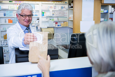 Pharmacist giving medicine package to customer
