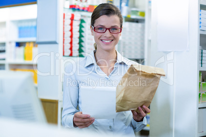 Pharmacist holding prescription and medicine package in pharmacy