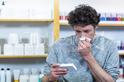Customer checking medicine box while sneezing