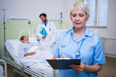 Nurse writing on clipboard