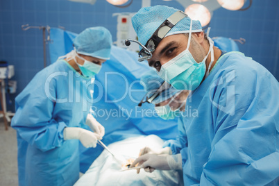 Surgeon looking at camera while colleagues performing operation