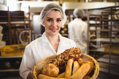 Female baker holding basket of bread and sweet food