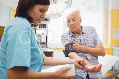 Female doctor checking blood pressure of patient