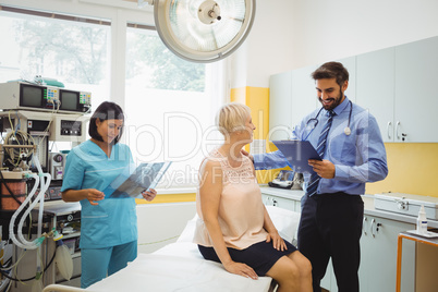 Male doctor interacting with a patient while nurse looking at x-