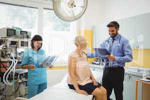 Male doctor interacting with a patient while nurse looking at x-