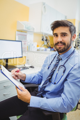 Portrait of doctor writing on a clipboard