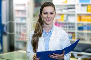 Pharmacist holding clipboard folder in pharmacy