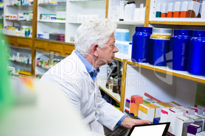 Pharmacist holding digital tablet while checking medicine