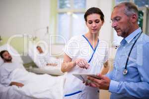 Doctor and nurse discussing over digital tablet