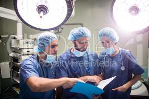 Surgeons discussing patient records in operation room