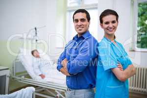 Smiling doctor and nurse standing with arms crossed