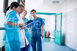 Doctor and surgeons discussing with report in corridor