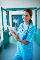 Portrait of surgeon using digital tablet in corridor