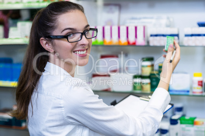 Pharmacist writing on clipboard while checking medicine in medic