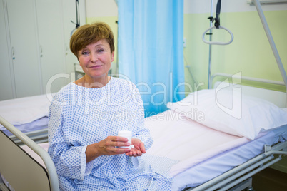 Portrait of senior patient sitting on a bed holding medicine