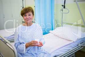 Portrait of senior patient sitting on a bed holding medicine