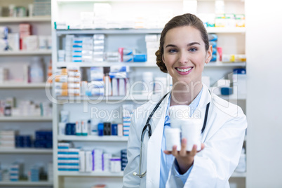 Smiling pharmacist showing medicine container in pharmacy