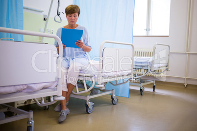 Senior patient sitting on a bed with report