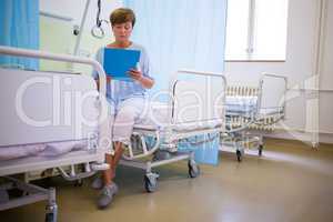 Senior patient sitting on a bed with report