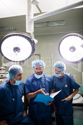 Surgeons discussing patient records in operation room