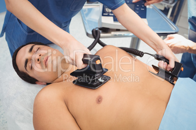 Female surgeon resuscitating an unconscious patient with a defib