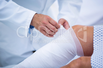 Doctor bandaging leg of patient