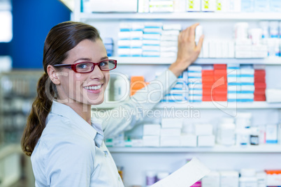 Pharmacist holding prescription while checking medicine in pharm